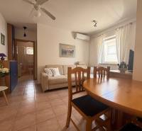 Living room in a two-room apartment with a dining table, sofa, and air conditioning.