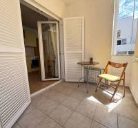 A balcony in a 2-room apartment with white blinds and a wooden chair.