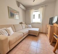 Living room with a sofa, air conditioning, television, and dining table in a 2-room apartment.