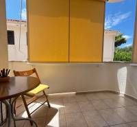 Balcony of a 2-room apartment in Novalja with a wooden table and a green view.