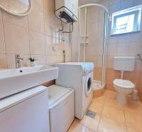 Bathroom in a 2-room apartment with a washing machine, shower, and toilet.