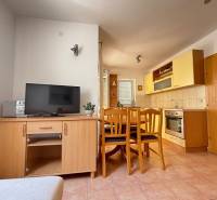 A kitchen with a dining area in a 2-room apartment, furnished with wooden furniture and appliances.