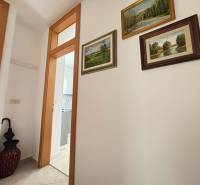 Hallway of a 3-room apartment with paintings on the wall and a door to the bathroom.