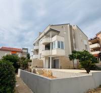 Apartment building with balconies in Novalja, 3-bedroom apartments, surrounded by greenery and shrubs.