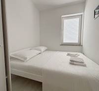 A bright bedroom with a bed, window, and white bed linen in a three-room apartment.