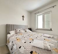 Bright bedroom with a comfortable bed in a 3-room apartment, cross on the wall.