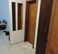 A hallway with a tiled floor, a mirror, and wooden doors in a 2-room apartment.