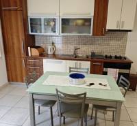 A kitchen in a 2-room apartment with wooden cabinets and a dining table with four chairs.