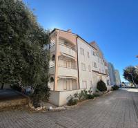 The exterior of an apartment building in the city of Novalja, for a 2-room apartment, with a paved road.