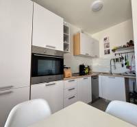 A kitchen in a 2-room apartment with modern white cabinets and built-in appliances.