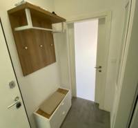 Hallway of a 2-room apartment with a coat rack, shoe cabinet, and white walls.