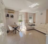Living room in a two-room apartment with a white couch and a dining table.