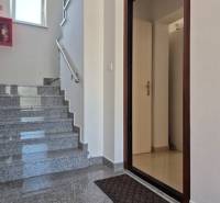A clean staircase with open doors in a 2-room apartment with a marble floor.