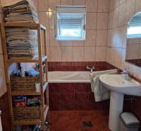 Bathroom in a 2-room apartment with a bathtub, shelves, and a window.