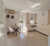A bright living room in a two-room apartment with a white sofa and a dining table.