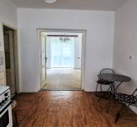 Kitchen in a 2-room apartment with a dining table, tiles, and entrance to the living room.