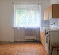 Simple kitchen with a gas stove, dining table, and chair in a 2-room apartment.