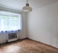 A room in a 2-room apartment with a bright window and wooden floor.