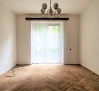 A room in a 2-bedroom apartment with wooden parquet floors and a chandelier.
