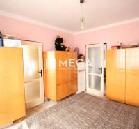 A room in a 2-room apartment with wooden cabinets and pink walls.