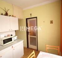 The kitchen in a 2-room apartment, with white cabinets and a microwave on the counter.