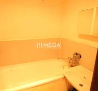 A bathroom with a bathtub and a sink in a 2-room apartment, simple interior.