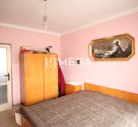 A bedroom in a 2-room apartment with pink walls, a wardrobe, and a painting above the bed.
