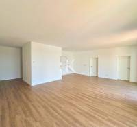 A spacious room with wooden flooring and white walls in a 3-room apartment.