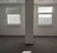 White offices with two windows and a pillar, smooth walls, unobtrusive carpet.