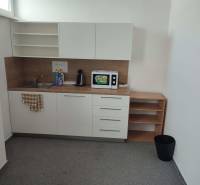 A kitchen counter in offices with a sink, microwave, and coffee maker.