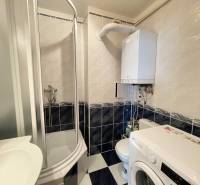 Bathroom in a 2-room apartment with a shower, washing machine, and gas boiler.