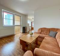 Living room in a two-room apartment with an orange sofa and a wooden table.