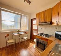 A kitchen with a stove, microwave, and a table with two chairs in a two-room apartment.