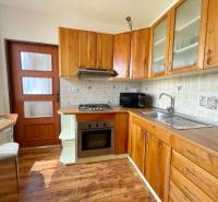 A kitchen in a 2-room apartment with wooden cabinets and appliances.