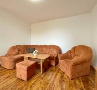 Living room with an orange sofa in a two-room apartment with wooden flooring.