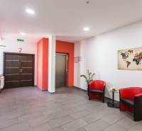 A hall with two red armchairs, a world map, and an elevator in the offices.