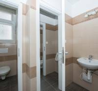 Bathroom in offices with beige tiles and a sink.