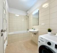 Bathroom with a bathtub, sink, washing machine, and radiator in a 2-room apartment.