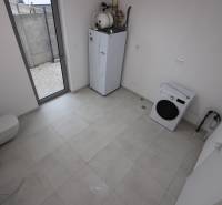 Laundry room in a family house with appliances and a large window.