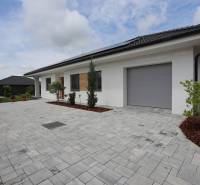 A family house in Piešťany with a garage, a paved courtyard, and greenery.