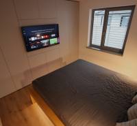 A bedroom in a family house with a TV, a large bed, and a window.