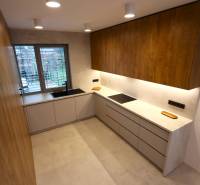 A kitchen with a wooden cabinet, a window, and gray cabinets in a family house.