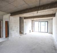 A bright room in a family house with a concrete ceiling, stairs, and glass doors.