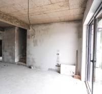 The interior of an unfinished family house, concrete walls and stairs lead to the upper floor.