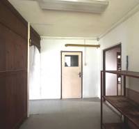 Commercial spaces with wooden walls and shelves in the interior, with two passages.