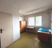 An office in commercial premises contains desks, chairs, cabinets, and a radiator.