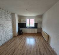 Interior of a family house with a kitchen unit, laminate flooring, and a brick wall.