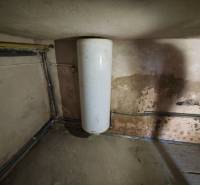 Water tank in a family house with a worn wall and piping.