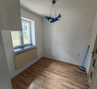 A room with a blue airplane-shaped chandelier, wooden floor, and a window, in a family house.
