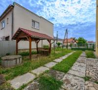 A family house in Vidiná with a carport and a well in a landscaped garden.